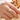Hand wearing gold-tone square cubic zirconia cluster ring, close-up with dried flowers