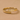 Primer plano de un anillo abierto envolvente dorado grabado con el texto Forever y un corazón sobre una superficie beige