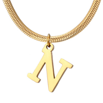 Dije de inicial N en tono dorado con cadena de serpiente, primer plano