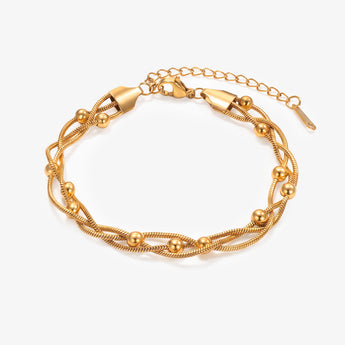 Pulsera de cadena en capas con cuentas en tono dorado y cadena extensora sobre fondo blanco