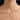 Mujer usando el collar con dije de inicial A en tono dorado, primer plano
