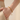 Mujer con pulsera de cadena en capas con cuentas en tono dorado y la mano en el bolsillo