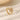 Anillo abierto envolvente en tono dorado con incrustación marmoleada blanca sobre una superficie color crema